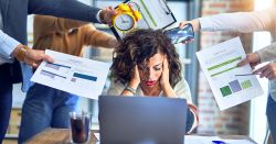 woman sitting at laptop overwhelmed with all the demands of her coworkers